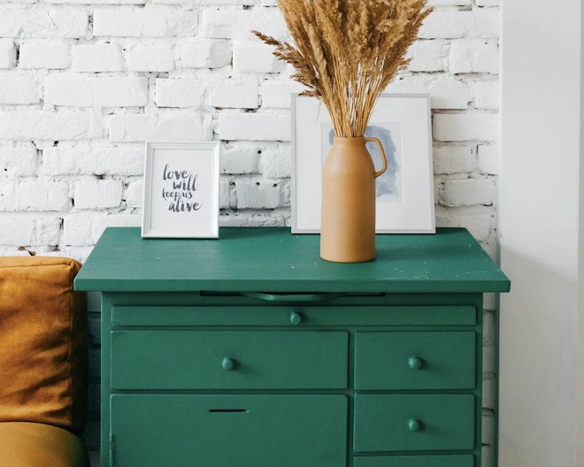 picture of green drawers with frames and a vase on top